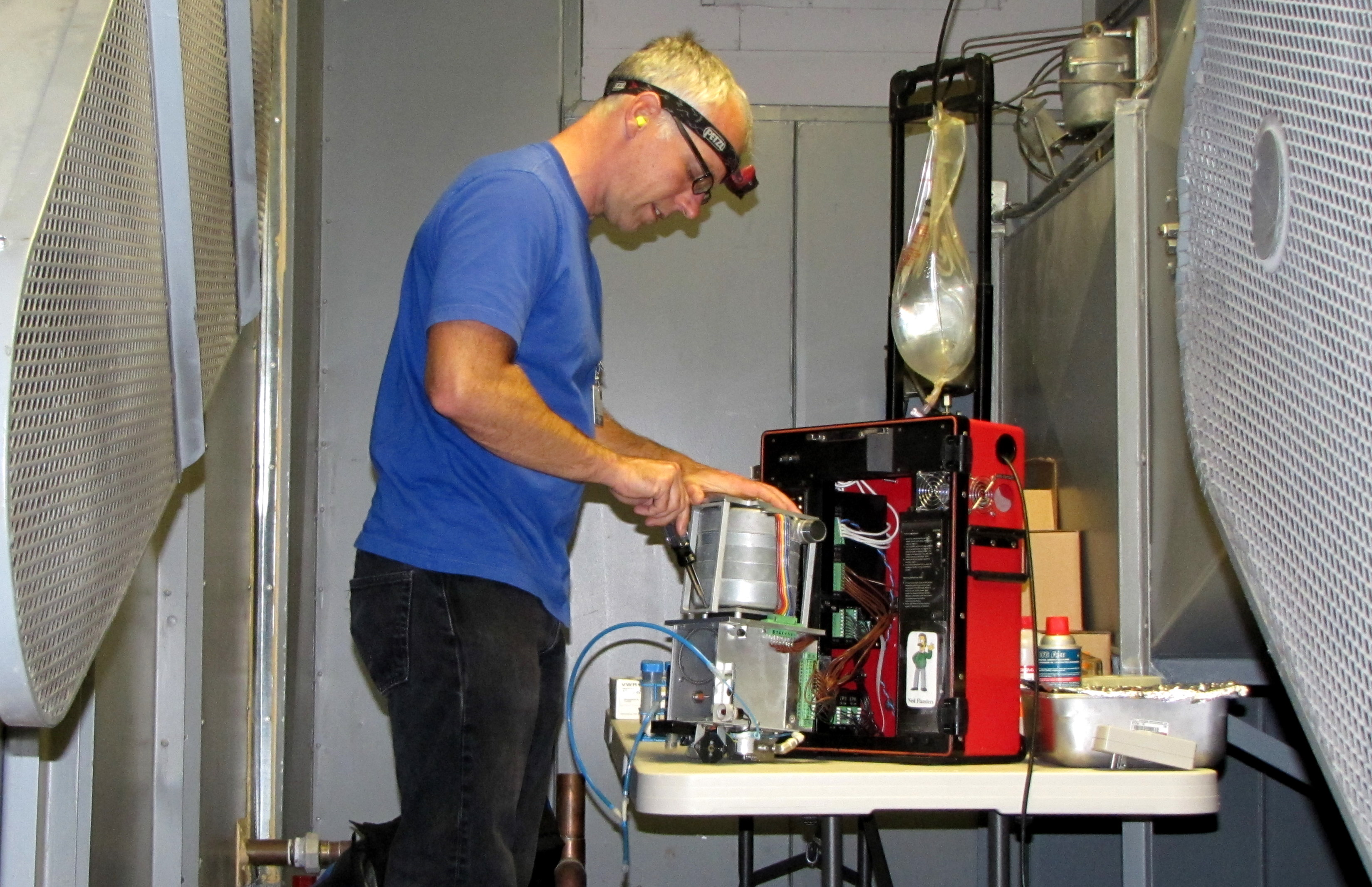 Field decontamination of an air sampler - this particular picture was taken in the air handling room of a medical center. Each machine was completely disassembled and all of the internal plumbing was replaced to prevent contamination. Those belts on either side of me let out a shrieking 110 dB of sound, hence the earplugs!